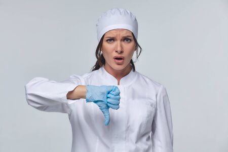 Medical concept of a female doctor in a white coat with a stethoscope, doctor. A female hospital worker looks at the camera and smiles, Studio, White backgroundの写真素材