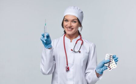 Medical concept of a female doctor in a white coat with a stethoscope, doctor. A female hospital worker looks at the camera and smiles, Studio, White backgroundの写真素材