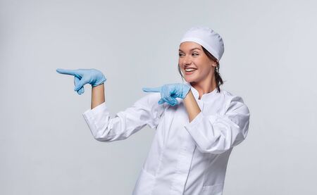 Medical concept of a female doctor in a white coat with a stethoscope, doctor. A female hospital worker looks at the camera and smiles, Studio, White backgroundの写真素材