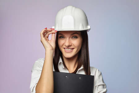 construction girl in a white helmet, holding a folder. the concept of a business woman who understands construction, repair and modernization ..の写真素材