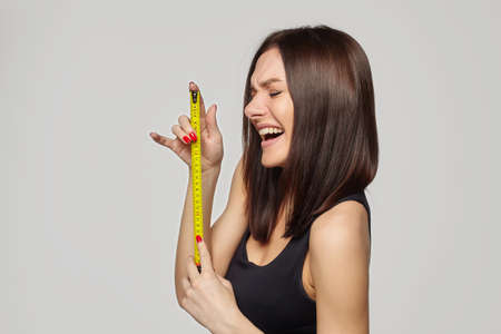 beautiful girl holds a measuring tape in her hands. the concept of imagination about the size of the penis ...の写真素材