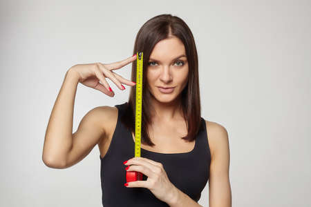 beautiful girl holds a measuring tape in her hands. the concept of imagination about the size of the penis ...の写真素材
