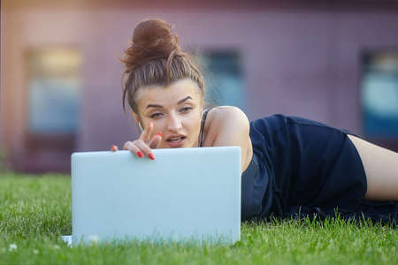 beautiful girl walks around the city, working on a laptop. holding a laptop and listening to music.の写真素材