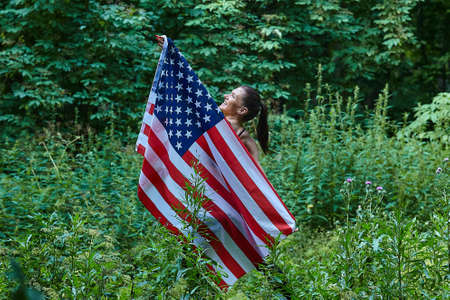 Attractive girl happily plays with fountain water stabs in city park.の写真素材
