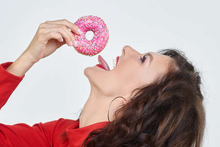 attractive girl in a red dress licks a donutの写真素材