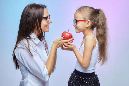 mother and daughter hold a large red Apple in their hands.の写真素材