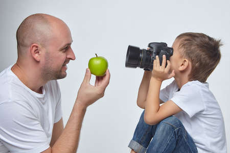 small boy photographs an adult man with a green Apple in his handsの写真素材