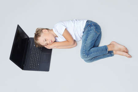 little boy fell asleep on a laptop with his hands folded under his head