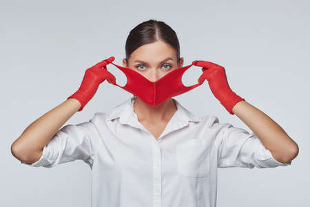 stylish young girl in a red mask and gloves. Concept of preventing coronavirus covid 19. Photo session in studio on white backgroundの写真素材