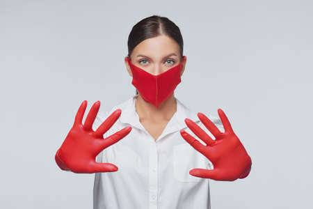 stylish young girl in a red mask and gloves. Concept of preventing coronavirus covid 19. Photo session in studio on white backgroundの写真素材