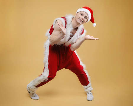 young guy dancer in a Santa suit on a yellow backgroundの写真素材
