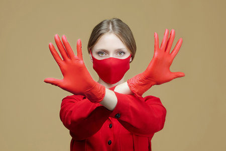 blonde in red gloves and a mask shows the sign STOP with her hands. the concept of preventing coronavirus covid 19.の写真素材