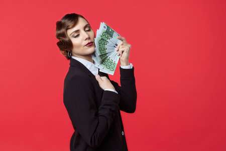 Attractive girl in retro style holding euro and dollars banknotes in different handsの写真素材