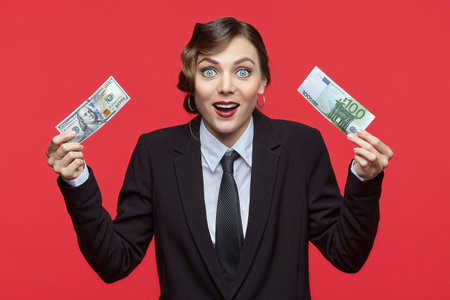 Attractive girl in retro style holding euro and dollars banknotes in different handsの写真素材