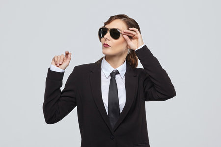 attractive woman with a retro hairstyle and a smile on her face. posing in a men's suit and sunglassesの写真素材