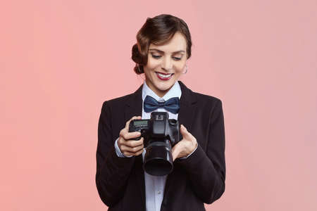 pretty girl photographer in a men's suit and retro hairstyle. posing with the camera in the studio...