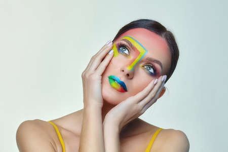 portrait of an attractive girl with bright makeup. A rainbow LGBT flag is depicted on her cheekの写真素材