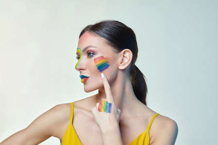 portrait of an attractive girl with bright makeup. A rainbow LGBT flag is depicted on her cheekの写真素材