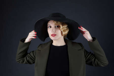 attractive blonde with a retro hairstyle in a black hat with a wide brimの写真素材