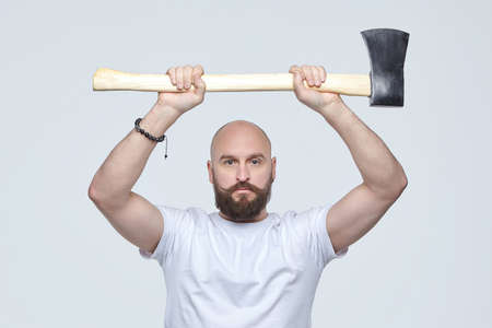 man of Caucasian appearance emotionally swings an ax. photo shoot in the studio