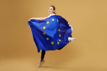 attractive blonde made posing with a rainbow LGBT flag. photo shoot in the studio on a yellow background.の写真素材
