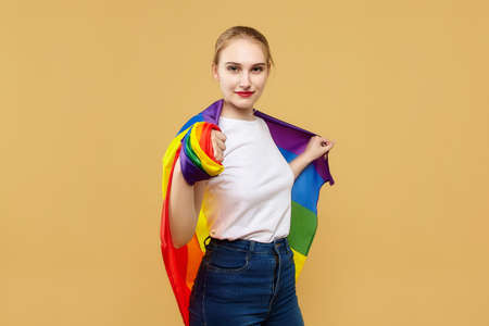 attractive blonde made posing with a rainbow LGBT flag. photo shoot in the studio on a yellow background.の写真素材