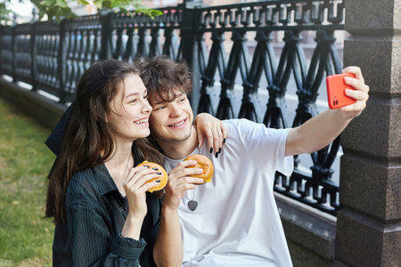 young girl holds a hamburger in her hands in front of her face.