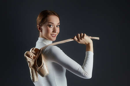 portrait of a ballerina holding pointe shoes. photo shoot in the studio on a dark background.の写真素材