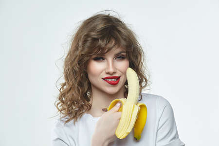 portrait of a beautiful girl who is preparing to bite off a banana.の写真素材