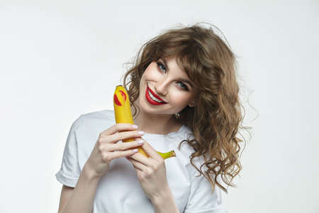 portrait of a beautiful girl holding a banana with a charming smile.の写真素材