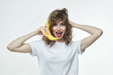 portrait of a beautiful girl holding a banana with a charming smile.の写真素材