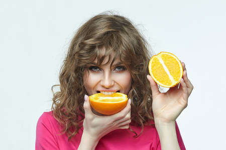 attractive girl with oranges in her hands photo shoot in the studio on a white background.の写真素材
