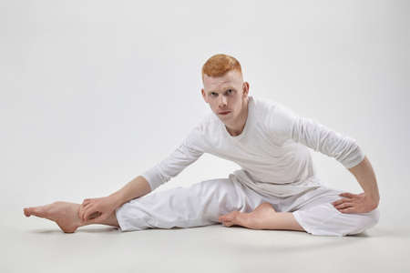 red-haired male dancer demonstrates the choreographic elements of the dance. photo shoot in the studio on a dark backgroundの写真素材