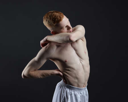 red-haired male dancer demonstrates the choreographic elements of the dance. photo shoot in the studio on a dark backgroundの写真素材