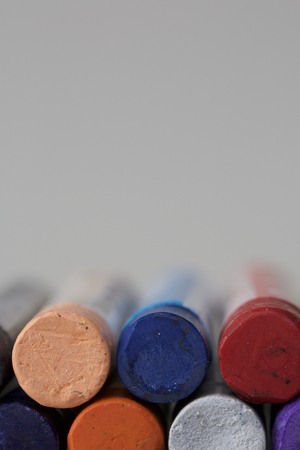 Set pastel art on a white background. Colors of rainbow. Pastel pencil arranged in two rows along the lower side of the vertical frame. Type in the end of pencils.の写真素材