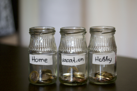 Three jars - piggy bank. In the miscellaneous expenses. They are glued to the tape to write her goal of spending. At the bottom poured a bit of coins. Budget Management.の写真素材