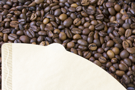 Roasted grains of black coffee. Paper filter for brewing coffee bean background.の写真素材