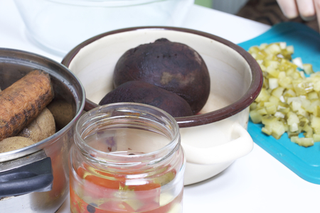 Vegetable salad vinaigrette. Russian recipes. Cooking Stages. On the table in dishes are cooked vegetables: potatoes, carrots and sugar beets. Nearby lie on a cutting board sliced pickles.の写真素材