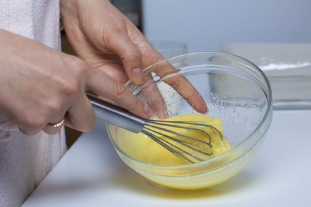 Preparation of homemade cakes. The woman beats the whisk sugar powder and chicken eggs, knocked into a cup.の写真素材