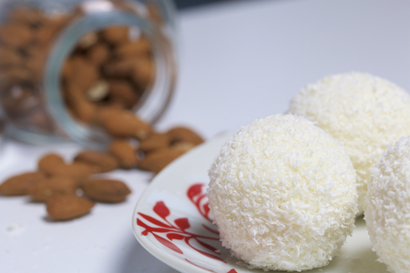 Preparation of Raffaello sweets at home. Ready-made sweets lie on a plate. On a background of a jar...