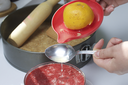 Cheesecake of cottage cheese and strawberries. Cooking process. The woman adds the juice squeezed from the lemon juice in a strawberry puree.の写真素材