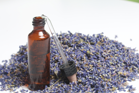 Dried flowers of lavender. A vial of dark glass with a pipette, sprinkled with a cluster of inflorescences of lavender. On a white background.の写真素材