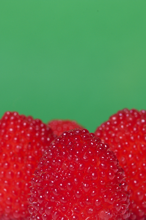 Large red berries are similar to raspberries. On a green background.