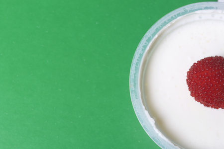 Jelly sour cream in a jar, decorated with raspberries. On a green background.の写真素材