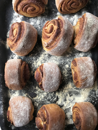 Preparation of buns with cinnamon at home. Ready ruddy buns lie on a tray.
