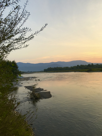 Sunset in the highlands. Soft sunrays illuminate the mountains on the horizon. Along the horizon, along the valley flows a mountain river.の写真素材