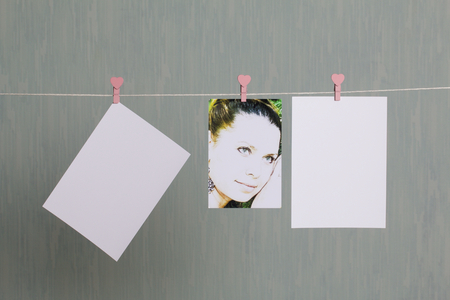 Photographic prints hang after developing on a cord and dry. There is a place to insert your content. Attached to the cord with clothes pegs in different positions. On a gray-green background.の写真素材