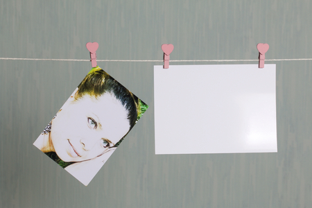 Photographic prints hang after developing on a cord and dry. There is a place to insert your content. Attached to the cord with clothes pegs in different positions. On a gray-green background.の写真素材