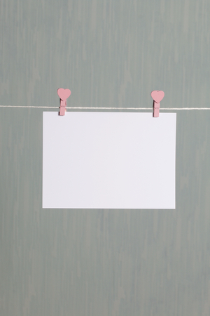 Photographic prints hang after developing on a cord and dry. There is a place to insert your content. Attached to the cord with clothes pegs in different positions. On a gray-green background.の写真素材