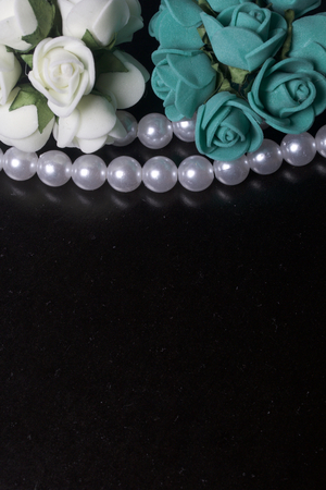 Ornaments for celebrations. Bouquet of artificial roses beige and emerald color. Framed with a string of pearly beads.の写真素材